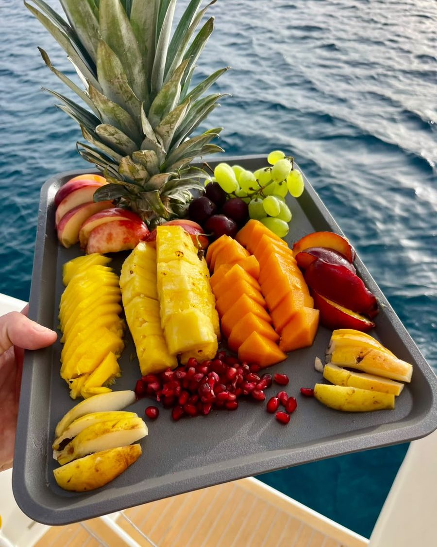Bandeja de frutas frescas servida en cubierta, con el mar de fondo