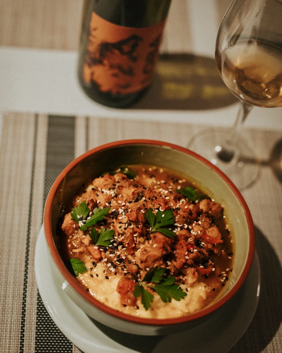 Plato de polenta con guiso, acompañado de vino